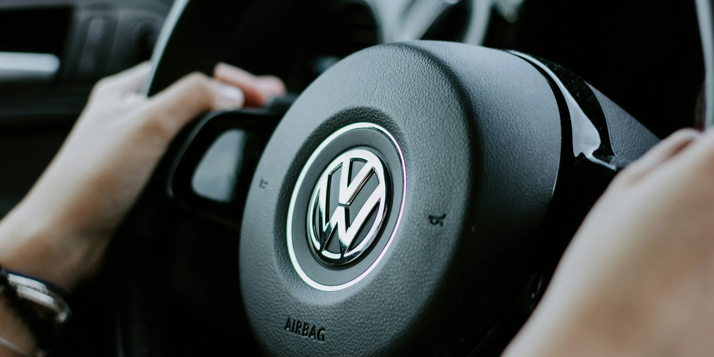 Driver's hands on a VW steering wheel